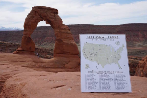 National Parks Checklist Map Poster Print in front of Delicate Arch at Arches National Park